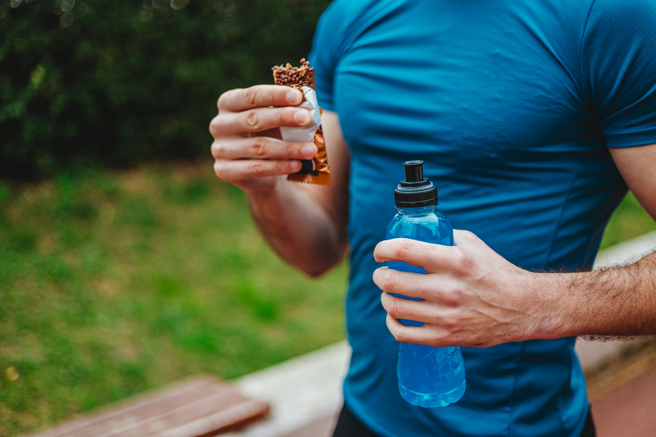 Man exercising and lives healthy life eating protein bar and drinking energy drink.