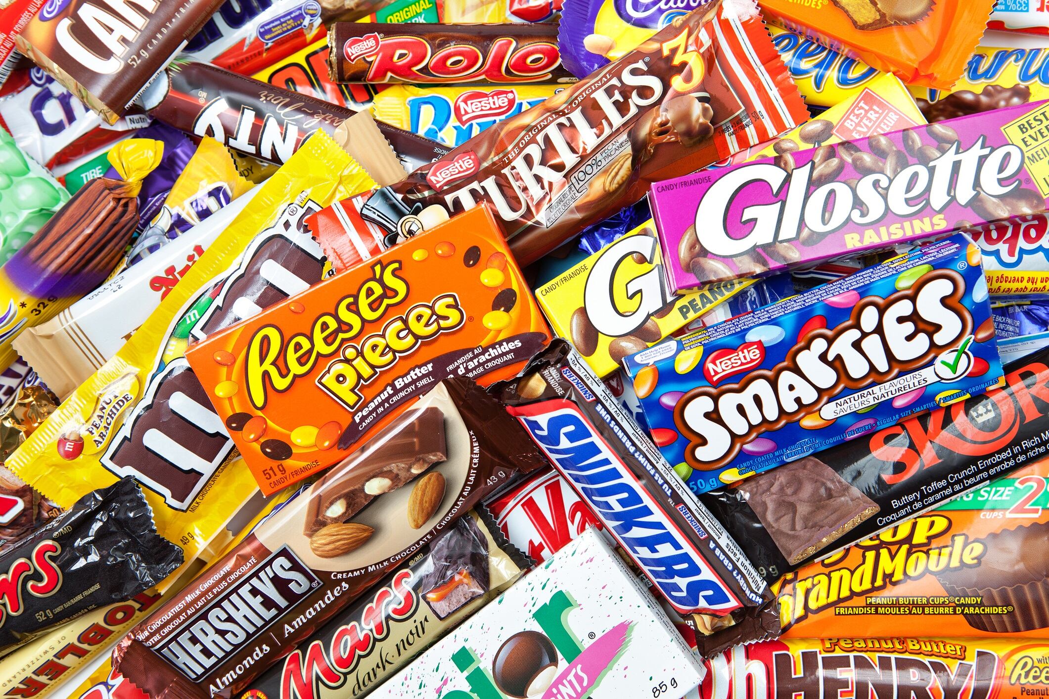 Variety of chocolate products made by various companies including Nestle, Hershey's, Mars Inc., and Cadbury isolated on a white background.