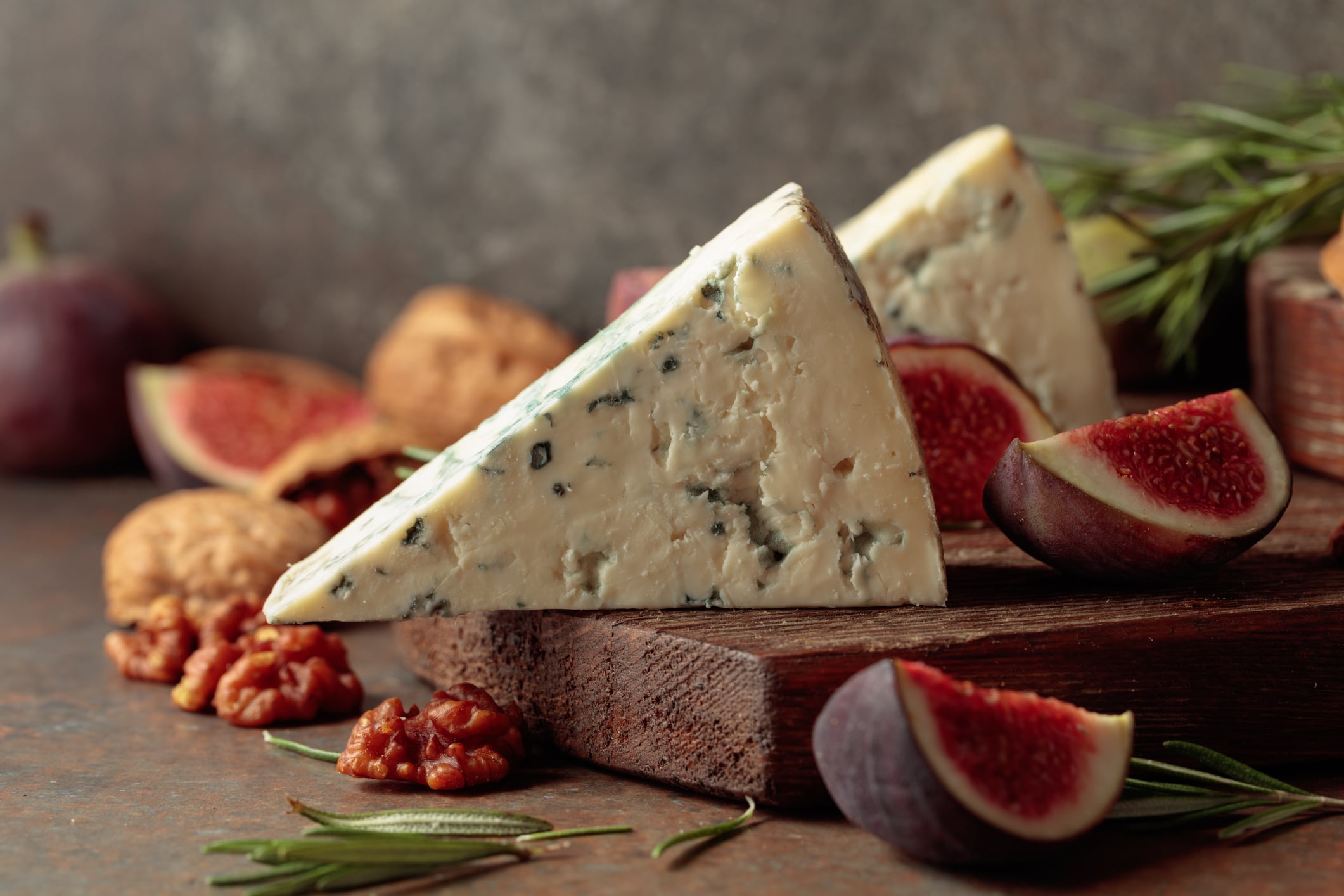 Blue cheese with fresh figs, rosemary, and walnuts on a vintage background.