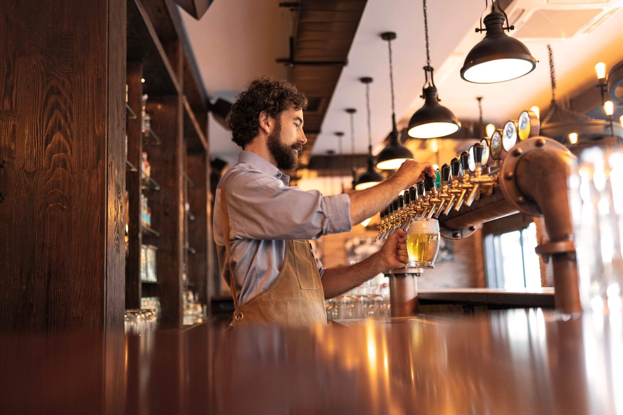 Bartender pouring fresh beer from beer tap