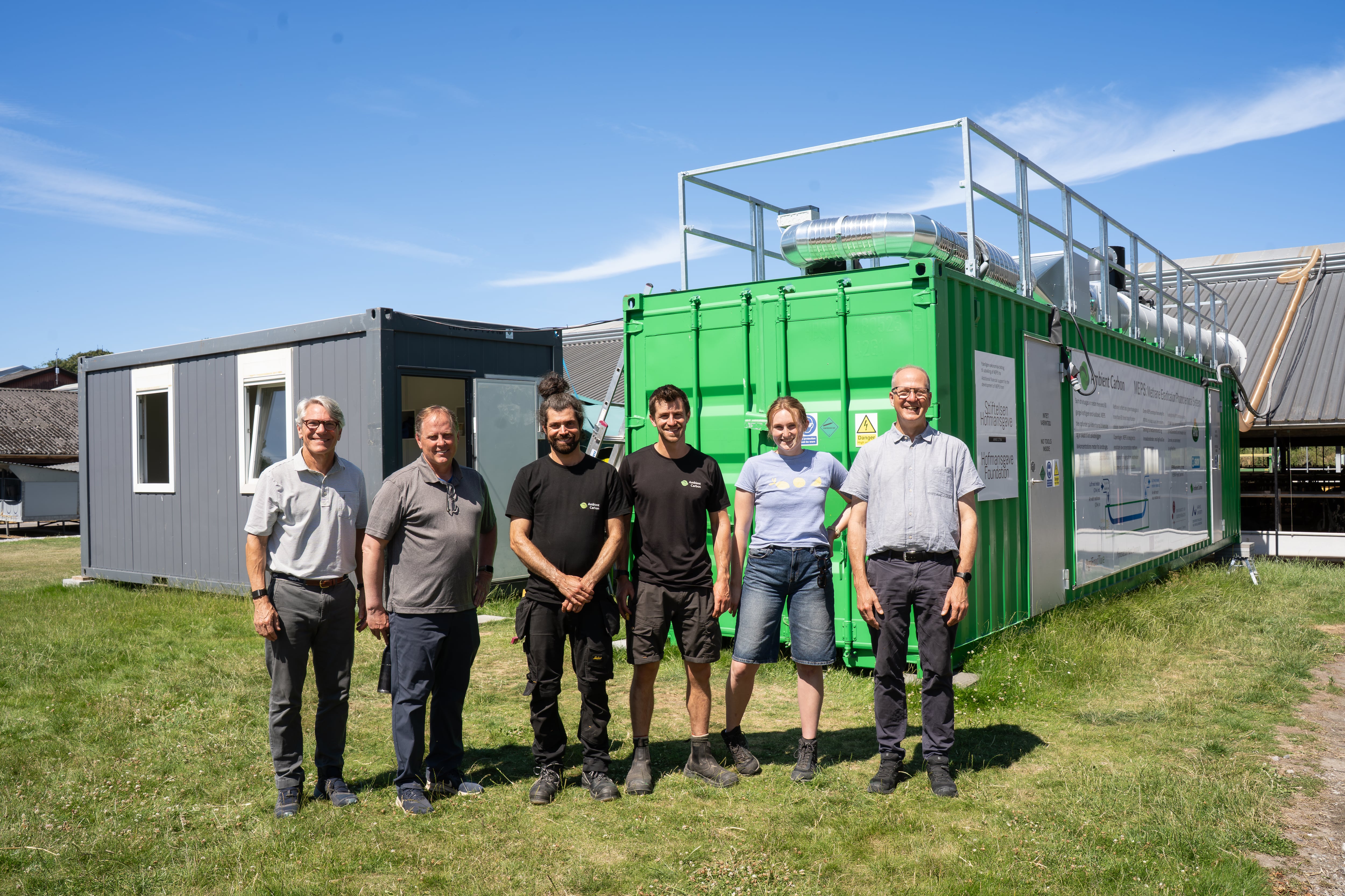 ambient carbon team poses in front of a meps installed at a danish dairy where it removed up to 90% of barn methane