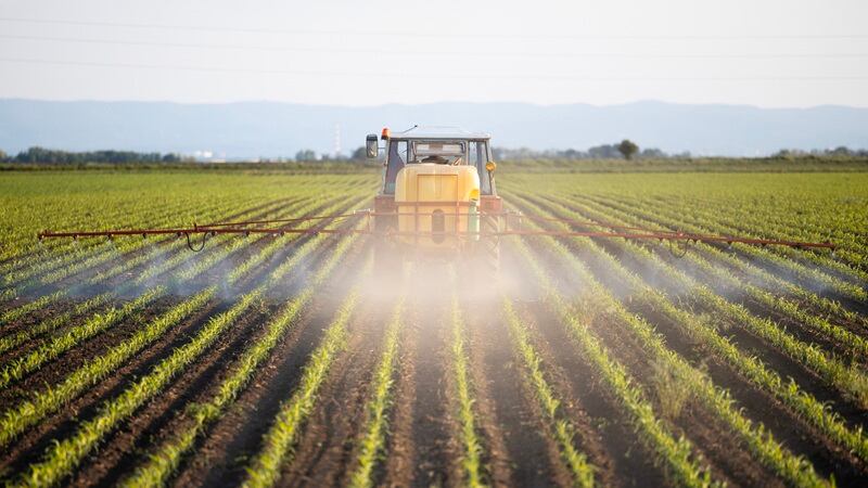 A tractor spraying fertilizer on a field