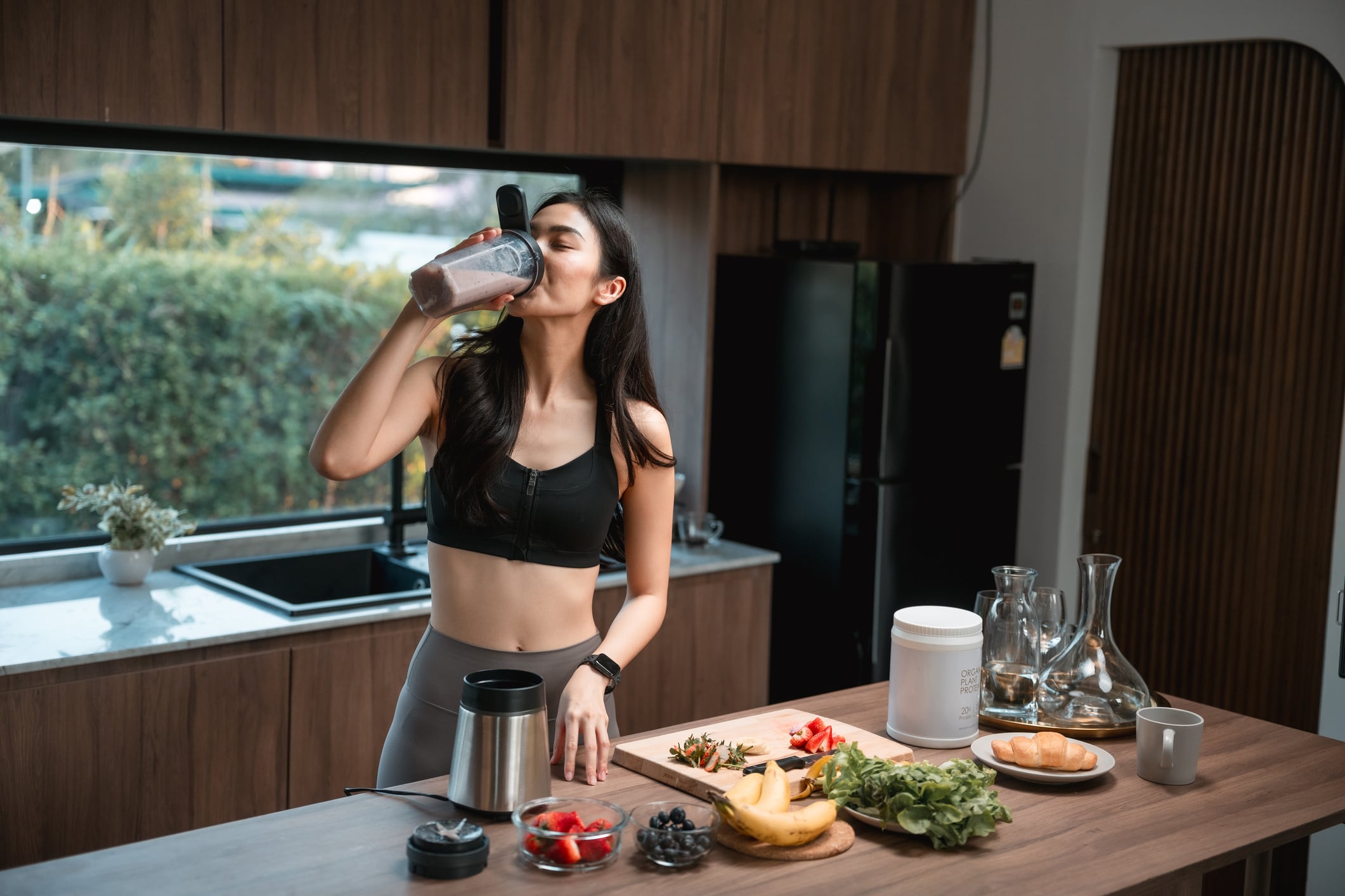Close-up shot of sporty woman enjoying a protein shake, taking a refreshing sip after her workout to replenish and nourish her body