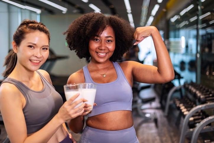 Two woman finish a workout by drinking milk.
