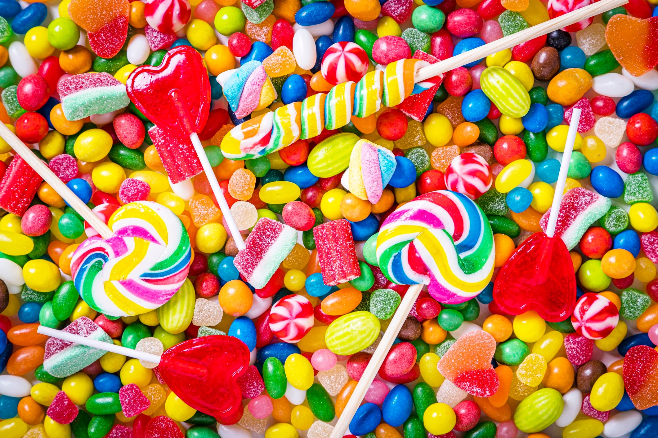 Top view of an assortment of multicolored candies, lollipops and jelly beans.