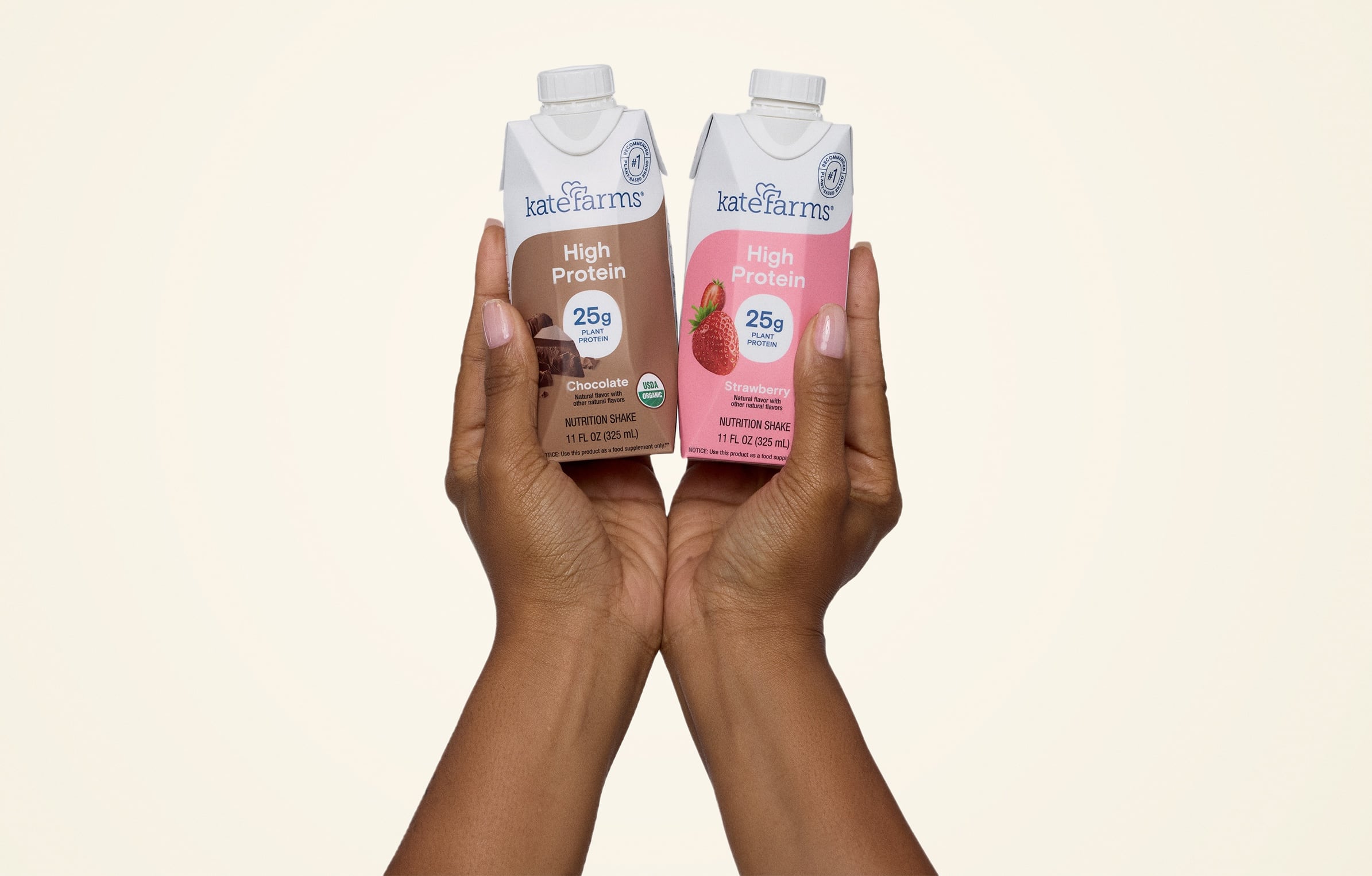 UHT carton protein shakes held up by a person on a beige background