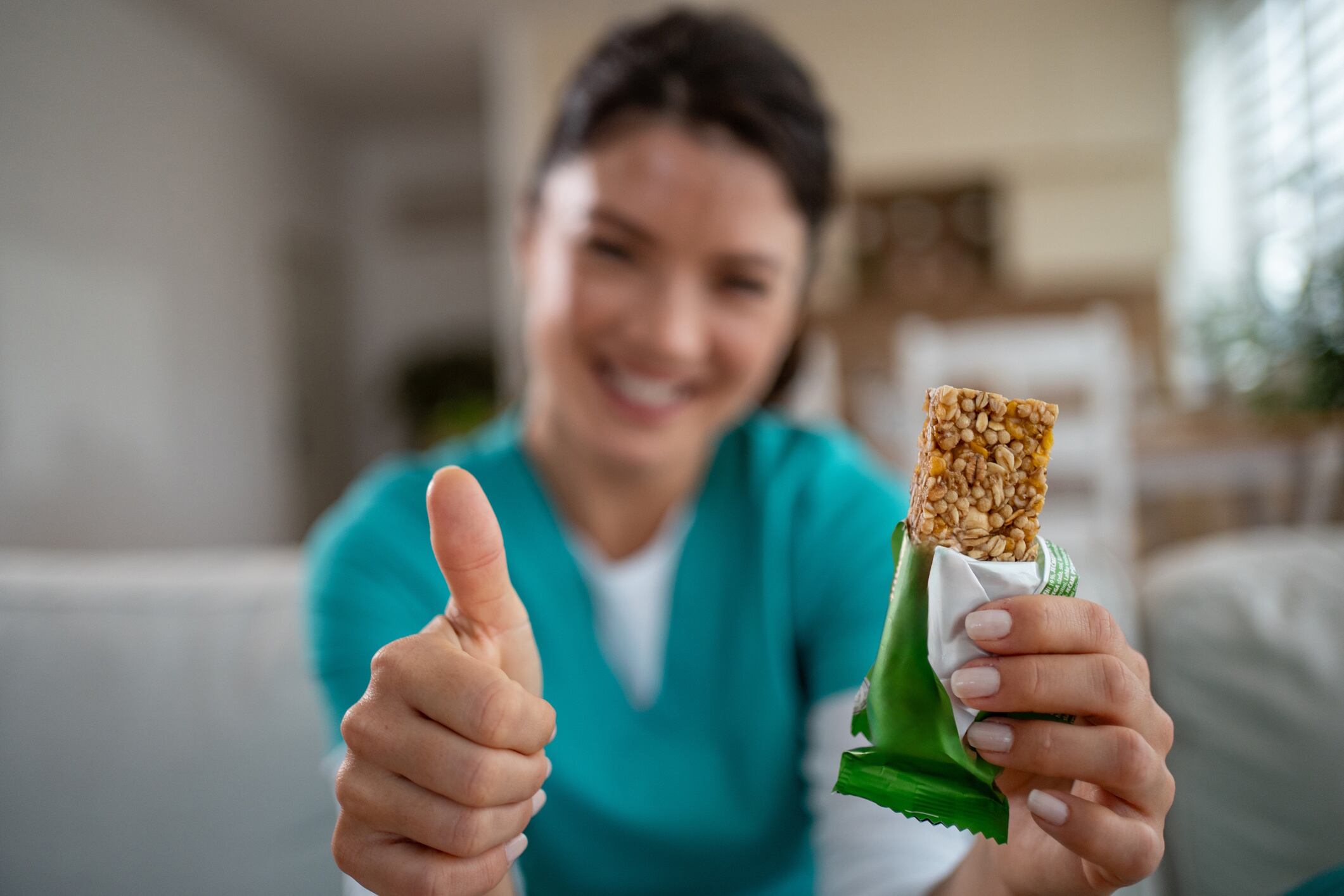 Happy woman recommending healthy granola bar snack Milan Markovic GettyImages