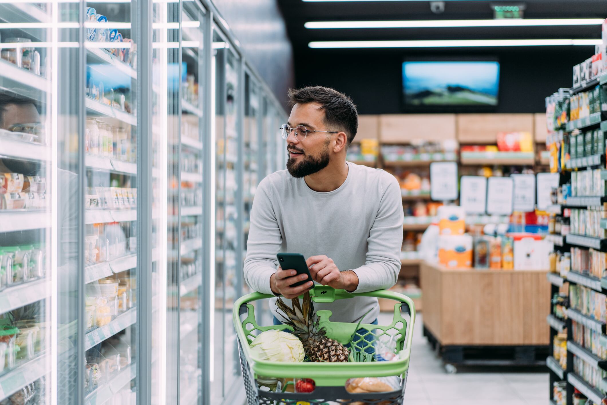 Shot of a young man using a smartphone while shopping in a grocery store.