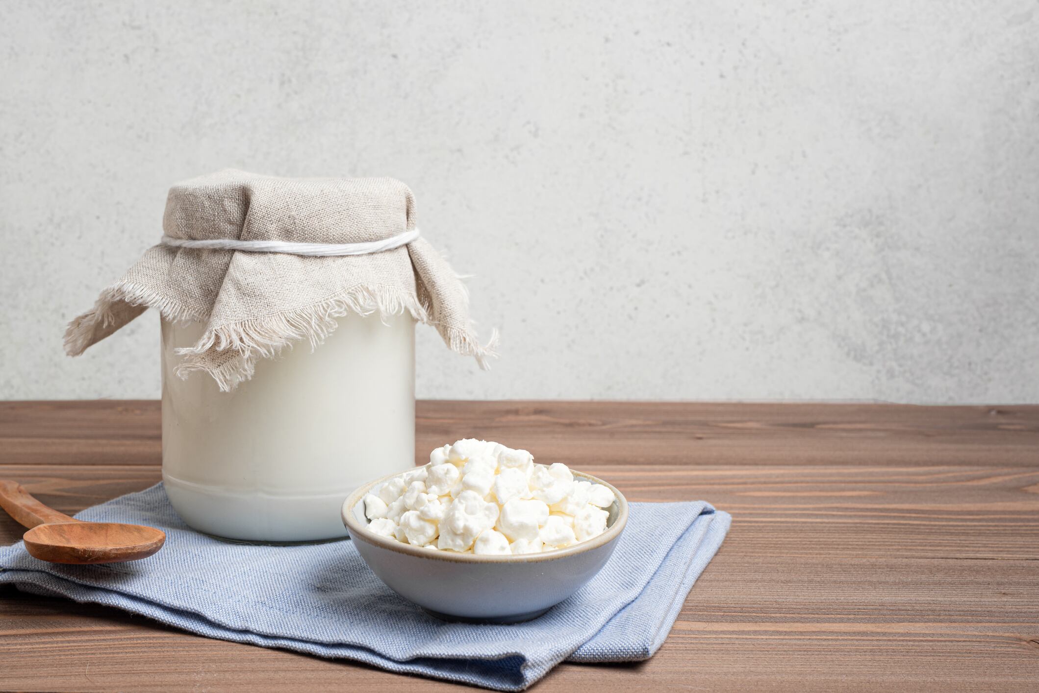 Milk kefir grains and jar of kefir on wooden table, copy space. Preparing healthy fermented probiotic milk kefir drink.