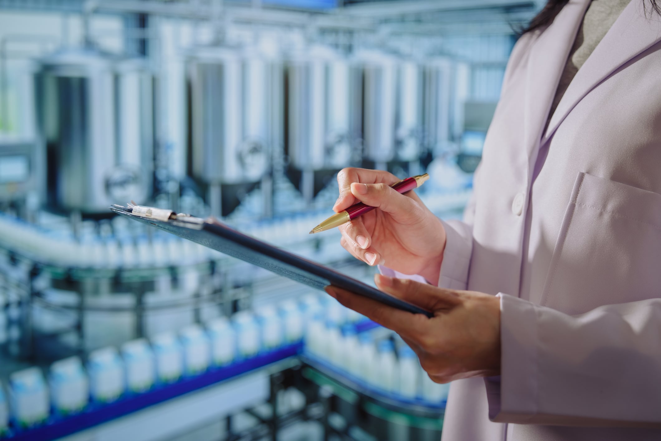 Asian young female quality control specialist holding a tablet in a modern dairy factory, approving production standards, ensuring food safety,hygiene compliance,smart manufacturing, industrial