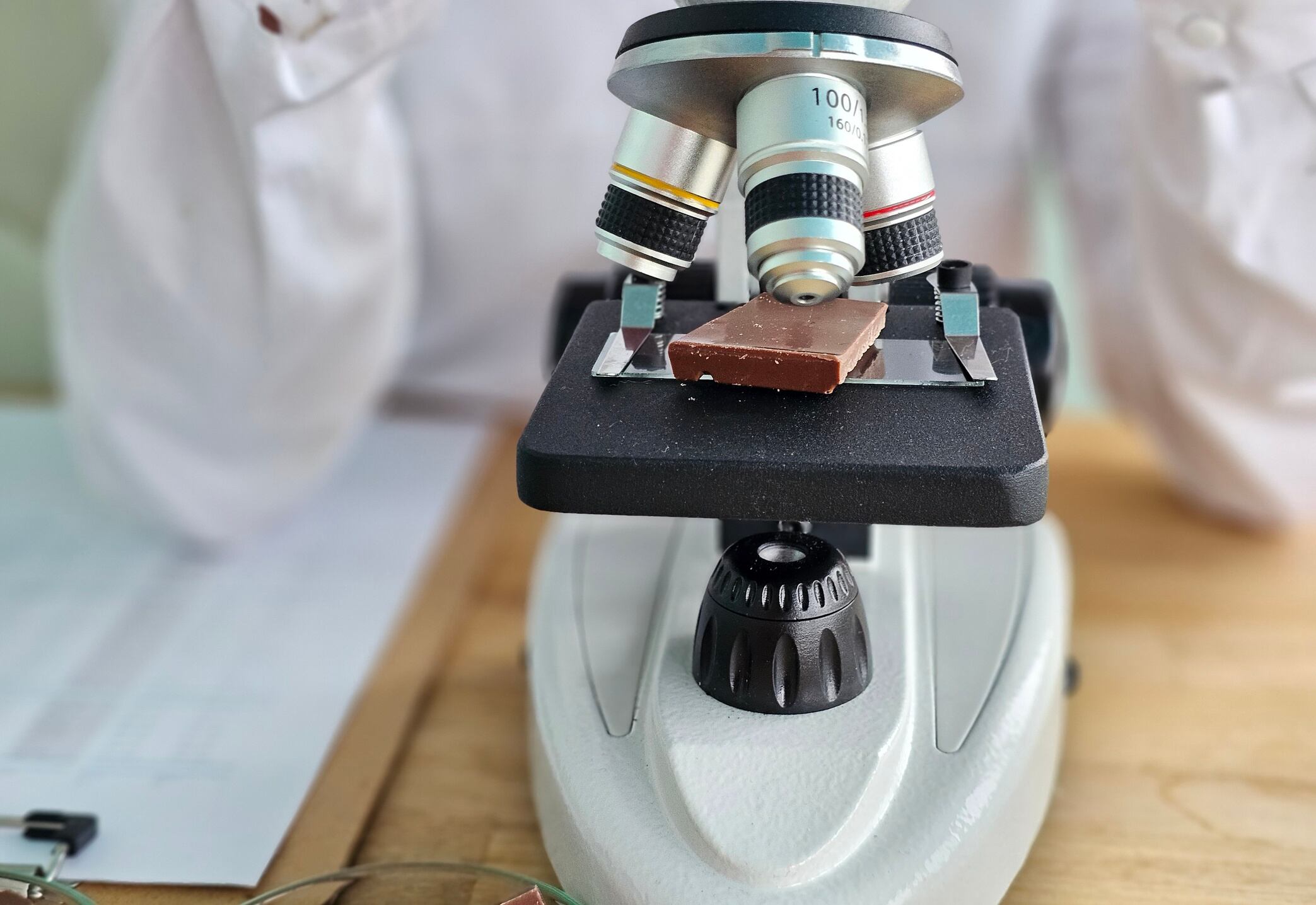 Scientist observes chocolate sample under microscope in laboratory for quality analysis and research insights Nadzeya Haroshka GettyImages-2255495570.jpg