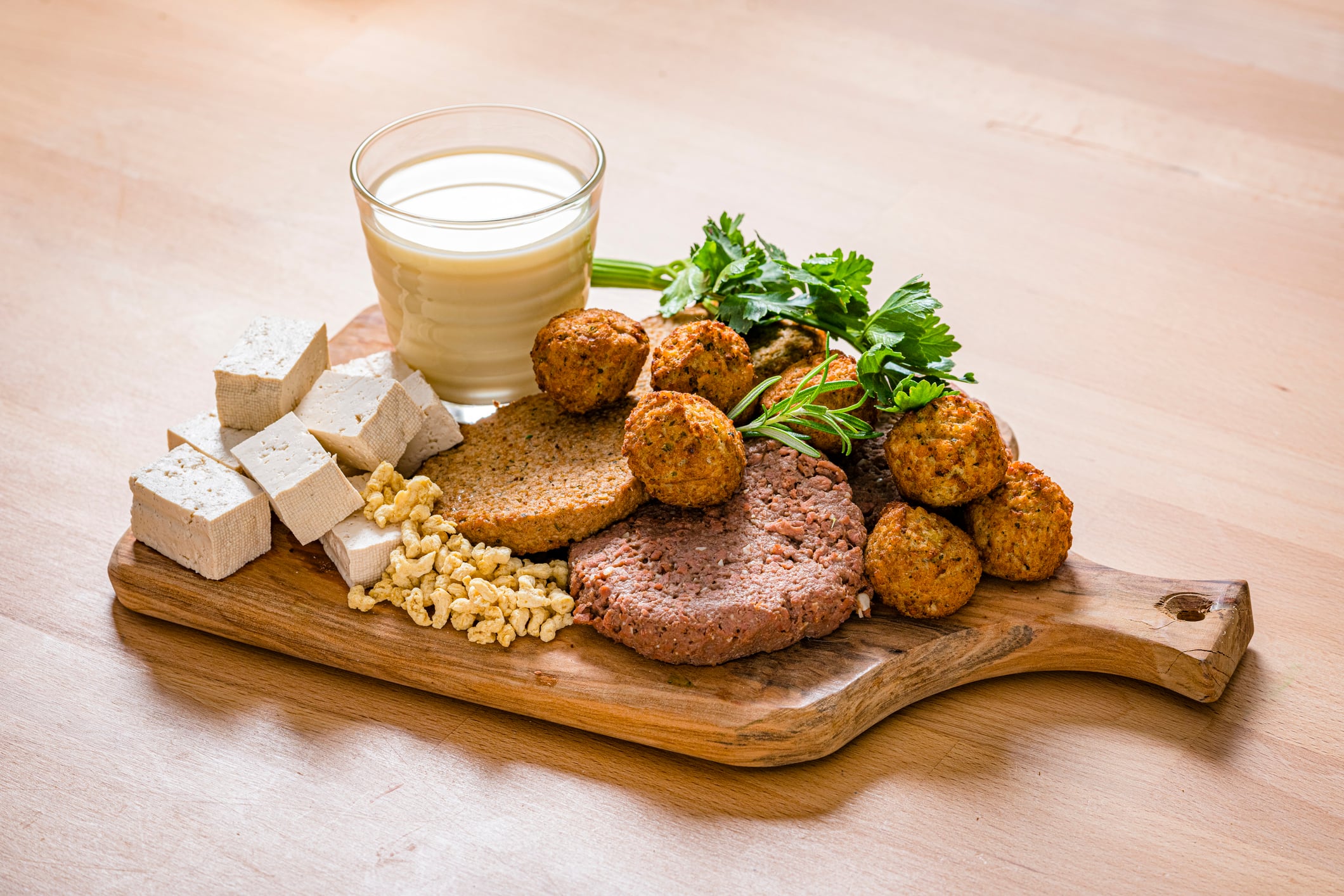 Cutting board filled with plant-based meat, tofu and soymilk shot on wooden table. High resolution 42Mp studio digital capture taken with SONY A7rII and Sony FE 90mm f2.8 macro G OSS lens