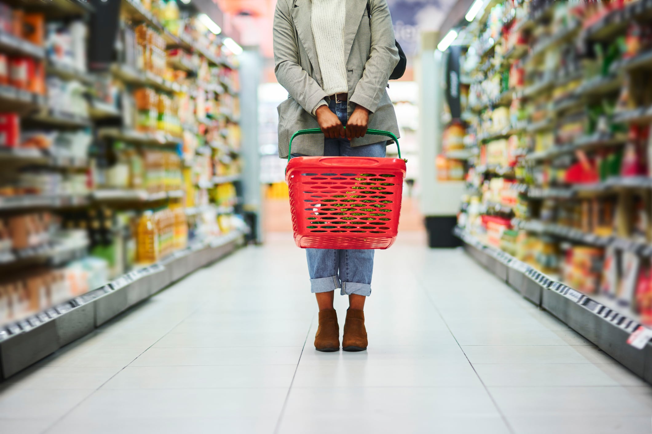 Supermarket aisle, woman and basket for shopping in grocery store. Customer, organic grocery shopping and healthy food on groceries sale shelf or eco friendly retail purchase in health shop